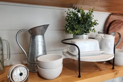 a shelf with dishes and a vase and a clock at Tiny Farmhouse on Wheels in Santa Clarita
