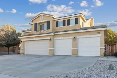 a house with two garage doors in a driveway at 5BR 3BA Home - King Beds - Fast Wifi home in Victorville