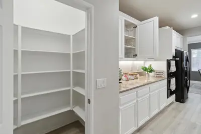 a kitchen with white cabinets and a refrigerator at 5BR 3BA Home - King Beds - Fast Wifi home in Victorville