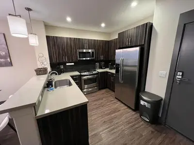 a kitchen with stainless steel appliances and wooden cabinets at Luxury Modern Condo 3-min from Six Flags w/PS5, 1GB Fast Wi-fi Kingbed in Santa Clarita