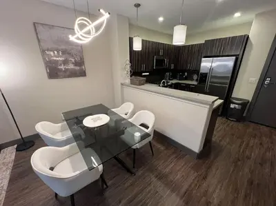 a dining room with a glass table and white chairs at Luxury Modern Condo 3-min from Six Flags w/PS5, 1GB Fast Wi-fi Kingbed in Santa Clarita