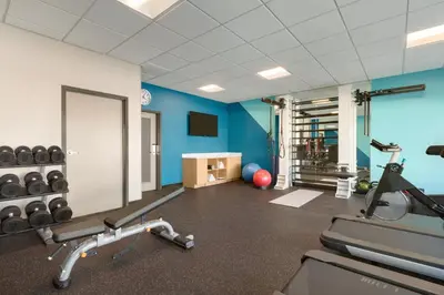 a gym with cardio equipment in a room with blue walls at avid hotel Victorville Hesperia by IHG in Victorville