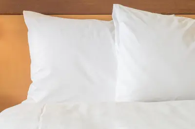 a bed with white sheets and pillows on it at avid hotel Victorville Hesperia by IHG in Victorville