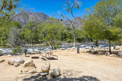 a picnic table on a dirt field next to a river at Brand New Cabin in Kernville