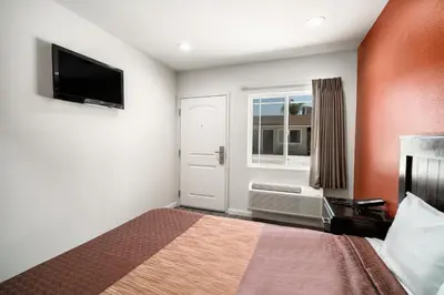 a small bedroom with a bed and a window at Bell Manor Motel in Bell