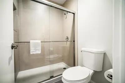 a bathroom with a toilet and a glass shower at Bell Manor Motel in Bell