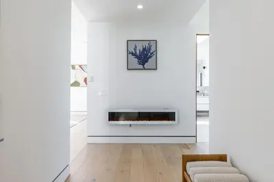 a living room with a fireplace in a white wall at The Penmar Retreat - Luxurious resort-style oasis in Los Angeles