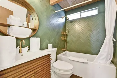 a bathroom with a toilet and a sink and a mirror at Quail's Call Big Bear~ Walk to Lake & Ski Resort in Big Bear Lake