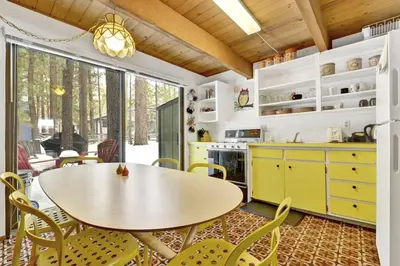 a kitchen with yellow cabinets and a table and chairs at Quail's Call Big Bear~ Walk to Lake & Ski Resort in Big Bear Lake