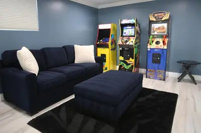 a living room with a couch and two arcade machines at Steps 2 Beach- Luxury Home, Game Room, Roof Deck, Firepit, Pets OK in Oxnard