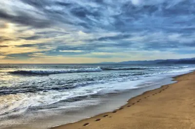 a beach with footprints in the sand and the ocean at Steps 2 Beach- Luxury Home, Game Room, Roof Deck, Firepit, Pets OK in Oxnard