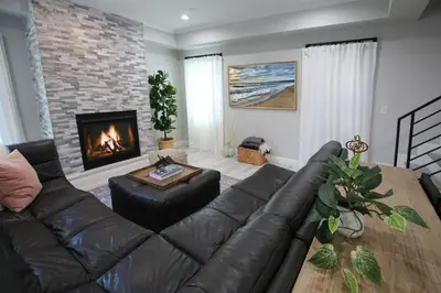 a living room with a leather couch and a fireplace at Steps 2 Beach- Luxury Home, Game Room, Roof Deck, Firepit, Pets OK in Oxnard