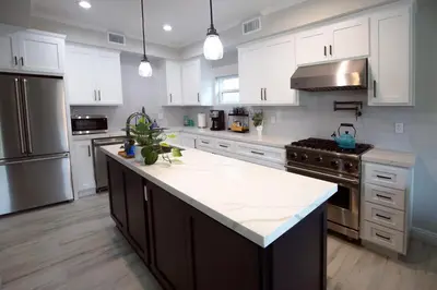 a kitchen with white cabinets and a large kitchen island at Steps 2 Beach- Luxury Home, Game Room, Roof Deck, Firepit, Pets OK in Oxnard