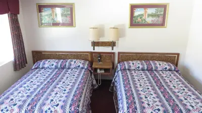 a room with two beds and a table with two lamps at Eagle Rock Motel in Los Angeles