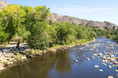 a river with rocks and trees and mountains in the background at Brandnew cabin in Kernville