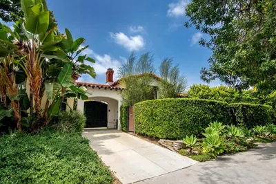 a white house with a gate and bushes at Beautiful Large 3 Bedroom 2 Bath Plus Pool and Jacuzzi in Los Angeles