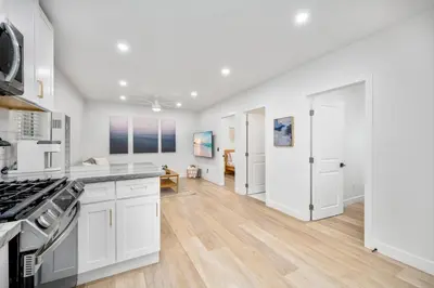an open kitchen with white cabinets and a hardwood floor at 130 Anderson St B in Sunset Beach