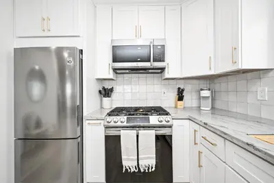 a kitchen with a stainless steel stove and white cabinets at Brand New Home by the Beach & Historic Sunset Water Tower in Sunset Beach