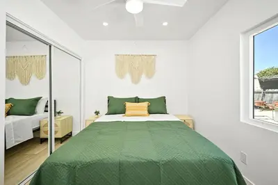 a bedroom with a bed with a green comforter at Brand New Home by the Beach & Historic Sunset Water Tower in Sunset Beach