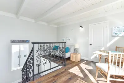 a white room with a staircase and a table at Sunset Island 3 Level Home on the Water sleeps 10 in Sunset Beach