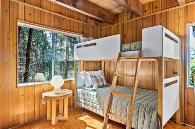 a bunk bed in a room with wooden walls at Pet & Kid Friendly Cozy Cabin, BBQ, Firepit, Outdoor Dining, Forest Views in Lake Arrowhead