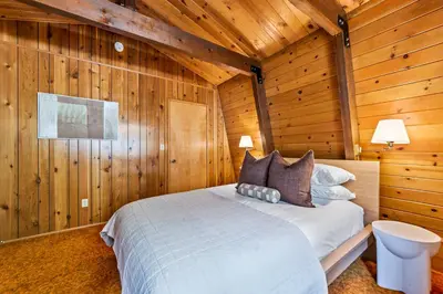 a bedroom with a bed in a wooden cabin at Pet & Kid Friendly Cozy Cabin, BBQ, Firepit, Outdoor Dining, Forest Views in Lake Arrowhead