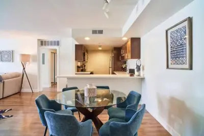 a dining room with a glass table and blue chairs at Blue Agate - Seaside Bright 2BR with Marina Views in Los Angeles