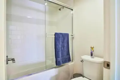 a bathroom with a toilet and a shower with a blue towel at Blue Agate - Seaside Bright 2BR with Marina Views in Los Angeles
