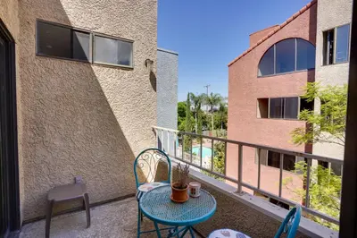 a patio with a table and chairs on a balcony at 1 Mi to the Ocean Long Beach Condo with Pool Access in Long Beach