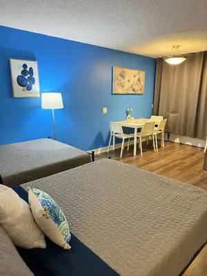 a room with two beds and a table and a blue wall at Hollywood Blvd Studio FREE DESIGNATED PARKING & WIFI in Los Angeles