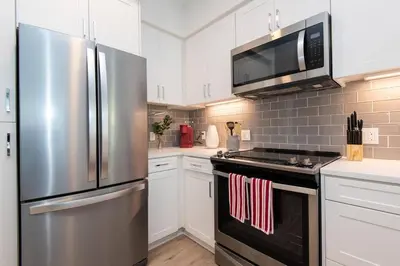 a kitchen with stainless steel appliances and white cabinets at Comfy Apt with pool & hot tub in downtown LA' in Los Angeles