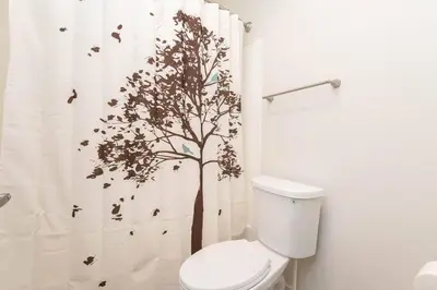 a bathroom with a shower curtain with a tree on it at Hollywood 1Bed Apt w Rooftop pool & Panoramic View in Los Angeles