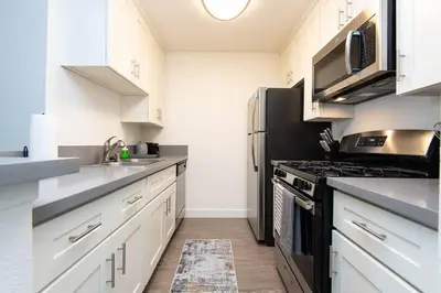 a kitchen with white cabinets and a black refrigerator at Hollywood 1Bed Apt w Rooftop pool & Panoramic View in Los Angeles