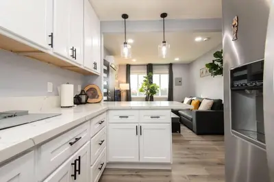 a kitchen with white cabinets and a living room at Lovely 3bedroom condo with free parking on premise in Los Angeles