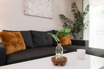 a living room with a black couch and a vase on a table at Comfy Cozy Apt with pool & hot tub in downtown LA' in Los Angeles