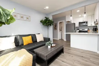a living room with a black couch and a kitchen at Lovely 3bedroom condo with free parking on premise in Los Angeles