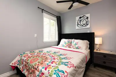 a bedroom with a bed with a colorful comforter and a window at Lovely 3bedroom condo with free parking on premise in Los Angeles