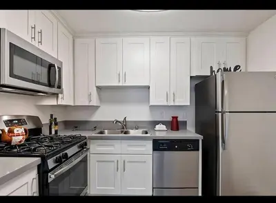 a kitchen with white cabinets and a stainless steel refrigerator at Hollywood 2Bed Apt w Rooftop pool & Panoramic View in Los Angeles