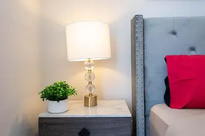 a lamp on a night stand next to a bed at Hollywood 2Bed Apt w Rooftop pool & Panoramic View in Los Angeles