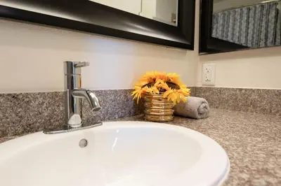 a bathroom counter with a sink and a vase of flowers at Hollywood 2Bed Apt w Rooftop pool & Panoramic View in Los Angeles
