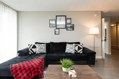 a living room with a black couch in a living room at Hollywood 2Bed Apt w Rooftop pool & Panoramic View in Los Angeles