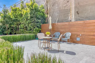a patio with a table and chairs and a fence at East Village Apartments in Long Beach