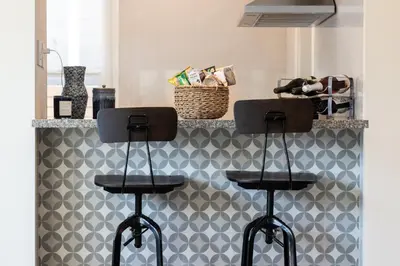 a kitchen with two stools in front of a wall at East Village Apartments in Long Beach