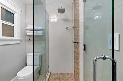 a bathroom with a toilet and a glass shower at East Village Apartments in Long Beach