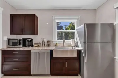 a kitchen with a stainless steel refrigerator and a sink at East Village Apartments in Long Beach