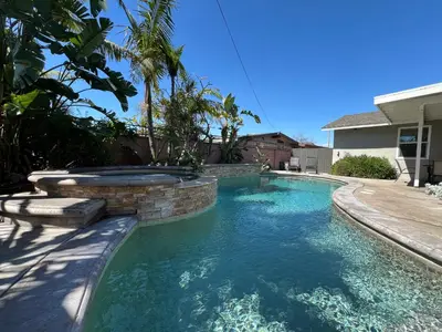 a swimming pool in a backyard with a stone retaining wall at Destination #04 in Anaheim