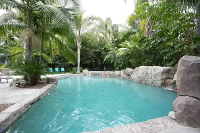 a swimming pool with a rock retaining wall and trees at Destination #03 in Fullerton