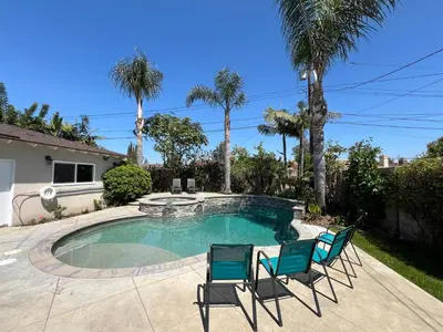 a swimming pool with two chairs and palm trees at Destination #23 in Anaheim