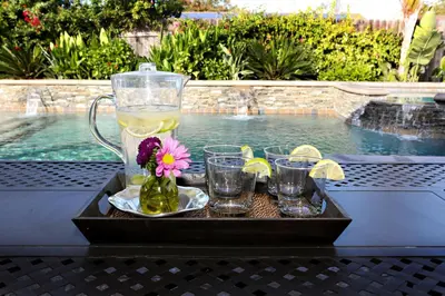 a tray with a pitcher and glasses on a table next to a pool at Nostalgic PoolJacuzzi Home: GameRm1.8 Mi 2Disney in Anaheim