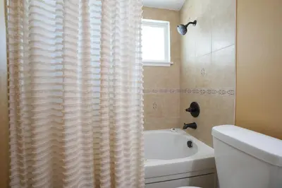 a bathroom with a white tub and a shower curtain at Nostalgic PoolJacuzzi Home: GameRm1.8 Mi 2Disney in Anaheim